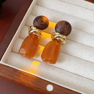 Close-up of vintage geometric wood and resin drop earrings with golden metal knot detail