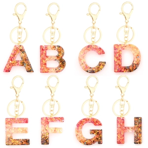 Detail view of crystal resin letter keychains A-H with gold flakes and lobster clasps
