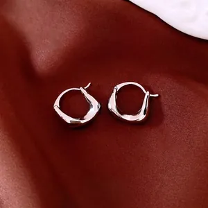 Chunky irregular silver oval earrings with 18K gold plating on red silk background