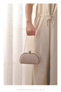 Champagne gold sequin evening clutch bag with pearl clasp and metal chain held by hand