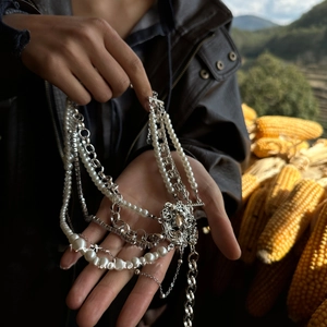 Detailed view of layered silver chains with pearl beads and round portrait relief pendant