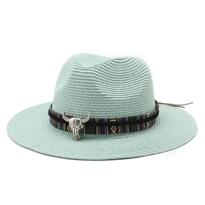 Dettaglio cappello di paglia menta con nastro etnico e ciondolo a testa di toro vintage