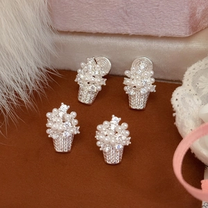 Detailed macro view of silver flower basket earrings featuring pearls and zircons