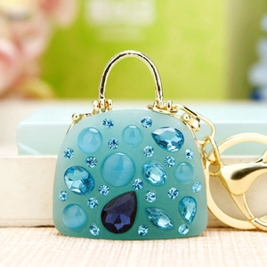 Detail of teal bag-shaped keychain with sparkling blue rhinestones and gold hardware