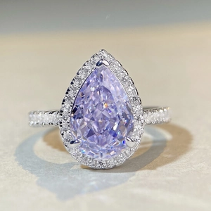 Close-up of pear-cut lavender gemstone ring with sparkling diamond halo and silver band
