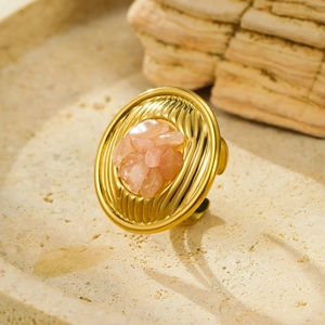 Detailed close-up of a gold textured ring with a pink natural stone on stone surface