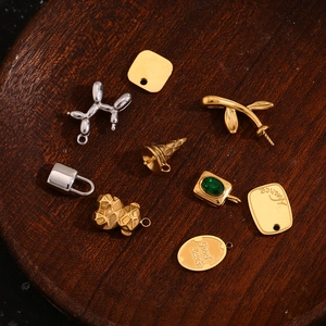 Mix of 18K gold plated balloon dog and mecha bear pendants on wooden tray