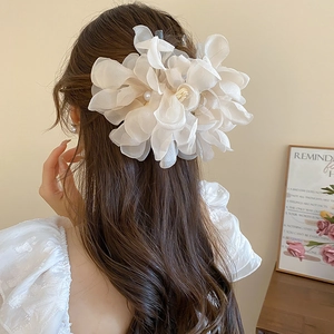 Detail of oversized cream organza flower hair claw with pearls on a female model