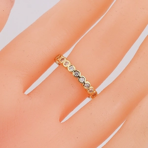 Detailed close-up of a gold-plated ring set with sparkling cubic zirconia on a finger