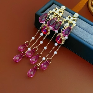 Detailed shot of long tassel earrings with pink crystals and pearls on velvet