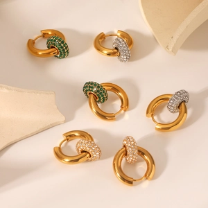 Dettaglio di orecchini in acciaio dorato 18K con ciondoli in zircone verde e bianco