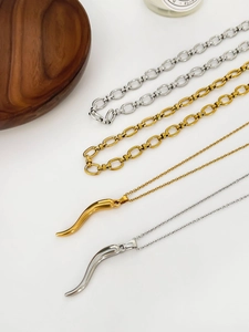 Detail of gold and silver italian horn pendants and stainless steel chains on wood