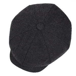 Detail of British herringbone tweed newsboy cap showing fiber texture and top button