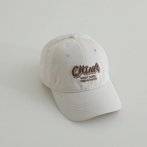 Detail view of cream baseball cap featuring brown 3D CHINA letter embroidery and stitching