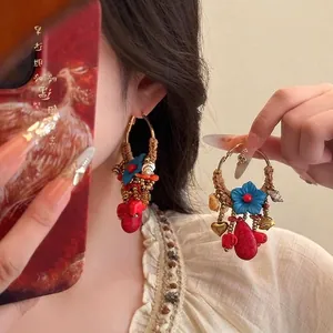 Détail de boucles d'oreilles bohèmes avec pierre rouge et coquillage sur le mannequin