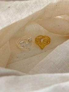 Dettaglio di anelli a cuore in argento e oro con trama lavica su tessuto di lino