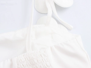 Detail des weißen Camisole-Tops mit dünnen Trägern, Brustfalten und elastischem Rückenteil