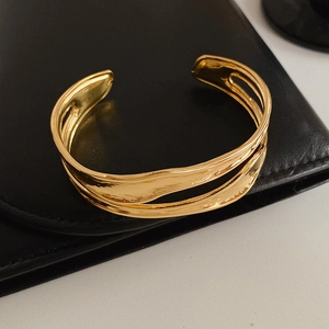 Macro detail of golden double-layer wavy textured open cuff bracelet on leather