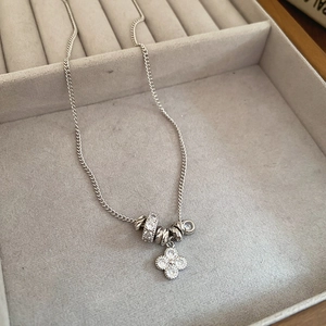 Detailed view of silver clover pendant with zircon inlay and metallic beads in a gift box