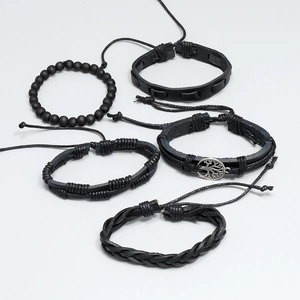 Macro shot of 5-piece black braided leather bracelet set with tree of life metal charm