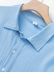 Detail of sky blue waffle textured shirt featuring short sleeves and a classic buttoned collar