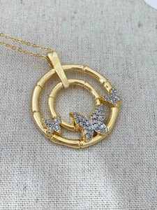 Detailed macro view of the gold bamboo-style double ring pendant with silver butterflies
