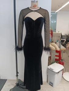 Detail of elegant black velvet evening dress with sheer mesh neckline and feather cuffs