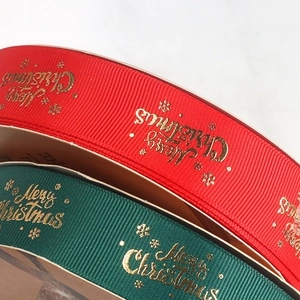 Close-up of red and green Christmas ribbons with gold Merry Christmas print and snowflakes