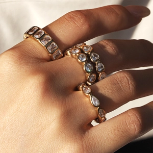 Macro shot of gold-plated alloy rings with cubic zirconia stacked on fingers