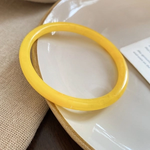 Detailed close-up of a minimalist yellow resin round bangle placed on a ceramic plate