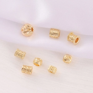 Detailed view of various gold metal beads with hollow and embossed designs on silk