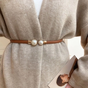 Detail of slim brown leather belt with gold pearl buckle on oatmeal cardigan