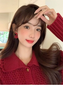 Close-up of red Chinese New Year earrings with golden Fu character on knitted red sweater