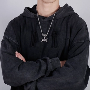 Detail of silver wolf head pendant with twist chain worn by male model on grey background