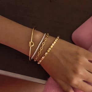 Classic 18K gold knot heart open bangle and bracelet stack on model wrist