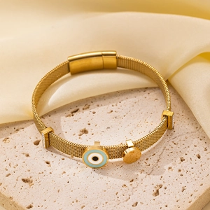 Detalle de pulsera de malla dorada con amuleto ojo turco azul y colgante redondo