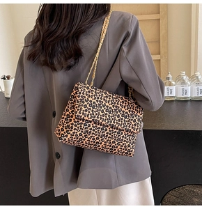 Close-up of stylish leopard print shoulder bag with gold chain strap on a model shoulder