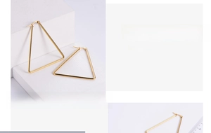 Macro shot of large triangular gold geometric earrings showing hinge detail and polished finish