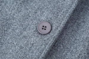Detailed macro view of gray wool coat texture with a purple four-hole button detail