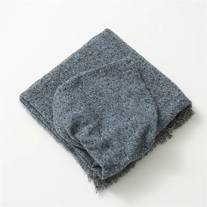 Detail of blue and grey plaid fabric texture with fringes on a folded cashmere poncho