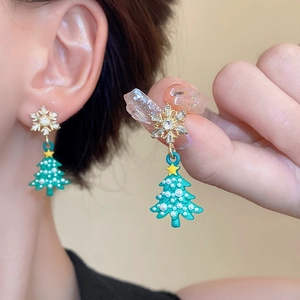 Detailed view of Christmas tree earrings with snowflakes, green enamel and pearls