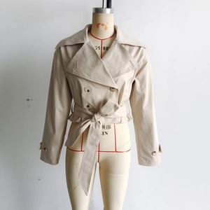 Détail d'un trench-coat court beige à double boutonnage avec ceinture sur un mannequin