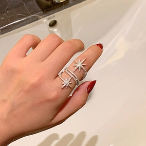 Close-up of star-shaped multi-layered silver ring with micro-pave zircons on finger