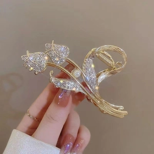 Detail of tulip metal hair claw clip with golden alloy finish, pearls and rhinestones