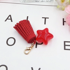 Close-up of a red star pendant with suede tassel and metal lobster clasp detail