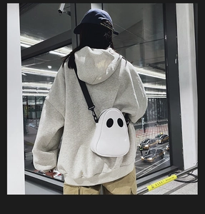 Detail of cute white ghost crossbody bag worn by a model in a modern urban setting