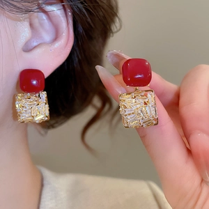 Gros plan sur les boucles d'oreilles carrées rouges avec cristaux et finition dorée