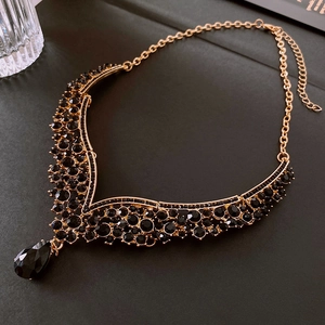 Vue détaillée du collier doré en V de luxe orné de pierres précieuses noires étincelantes
