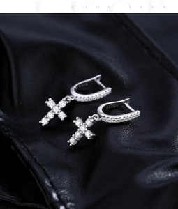 Macro shot of 925 sterling silver cross earrings with moissanite on black leather