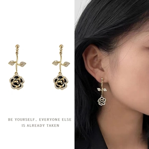 Detail of rose drop earrings with black enamel petals and crystals on model